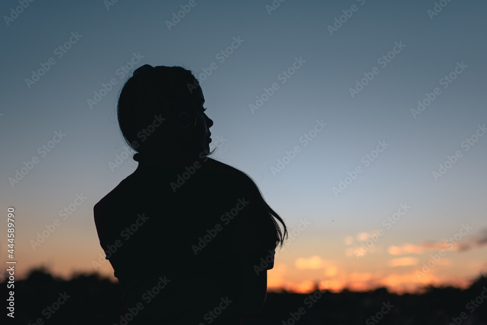 SILUETA DE MUJER CON AURICULAR ESCUCHANDO MÚSICA