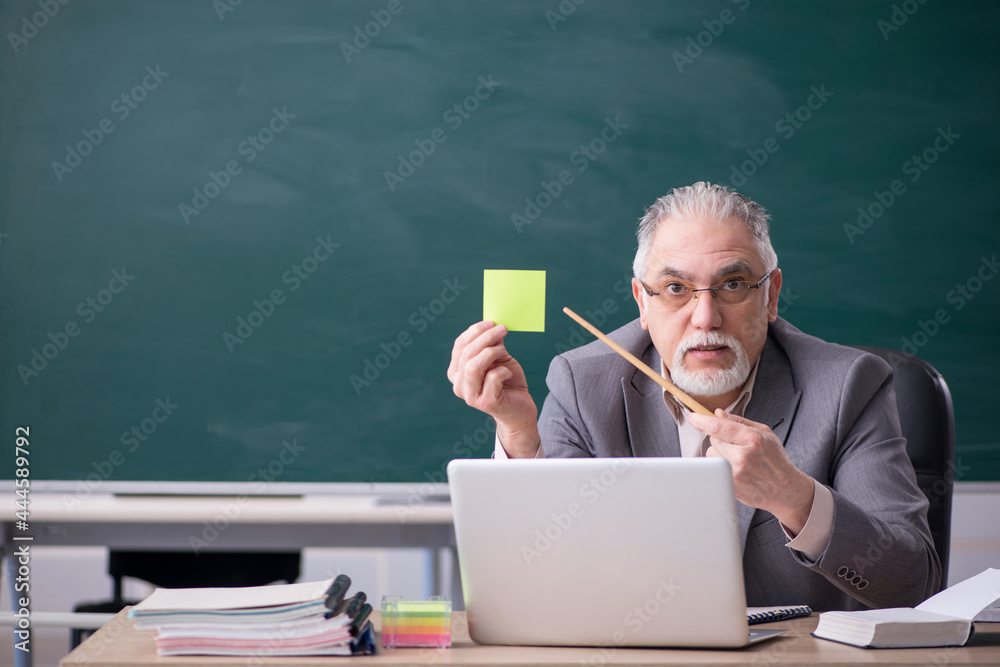 Old male teacher in front of blackboard Old male teacher in front of blackboard
