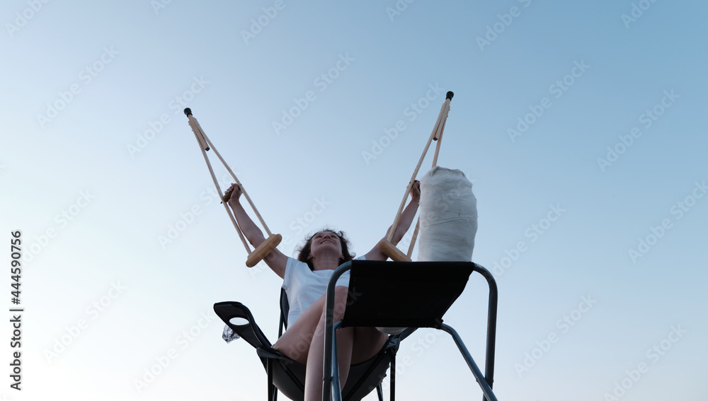 Fototapeta premium Woman holding orthopedic crutches above her head. Leg injury. Loss of mobility. Rehabilitation after a fracture