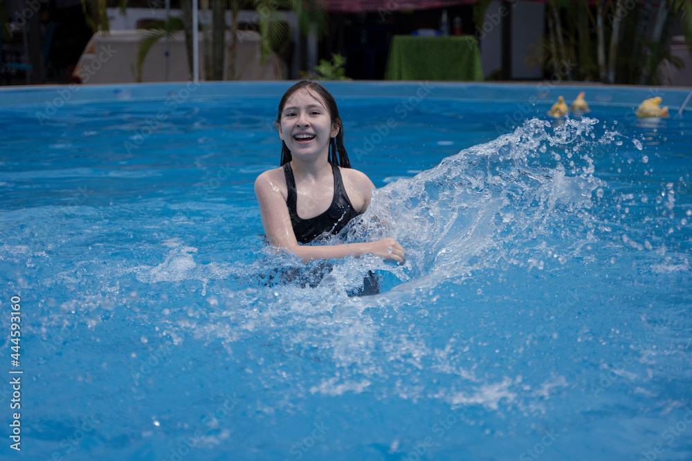 A girl is swimming in the pool, splashing water, splashing. Summer vacation, sunny day