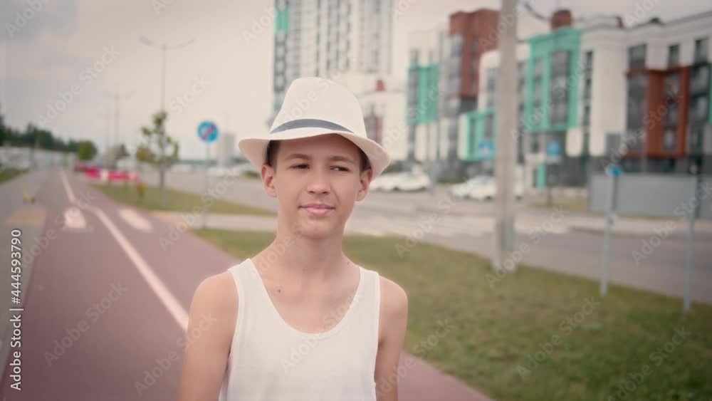 funny boy in a hat walking down the street in the summer, cinematic shot funny boy in a hat walking down the street in the summer, cinematic shot
