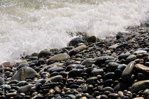 Incoming wave on a pebble beach, close-up. Background image.