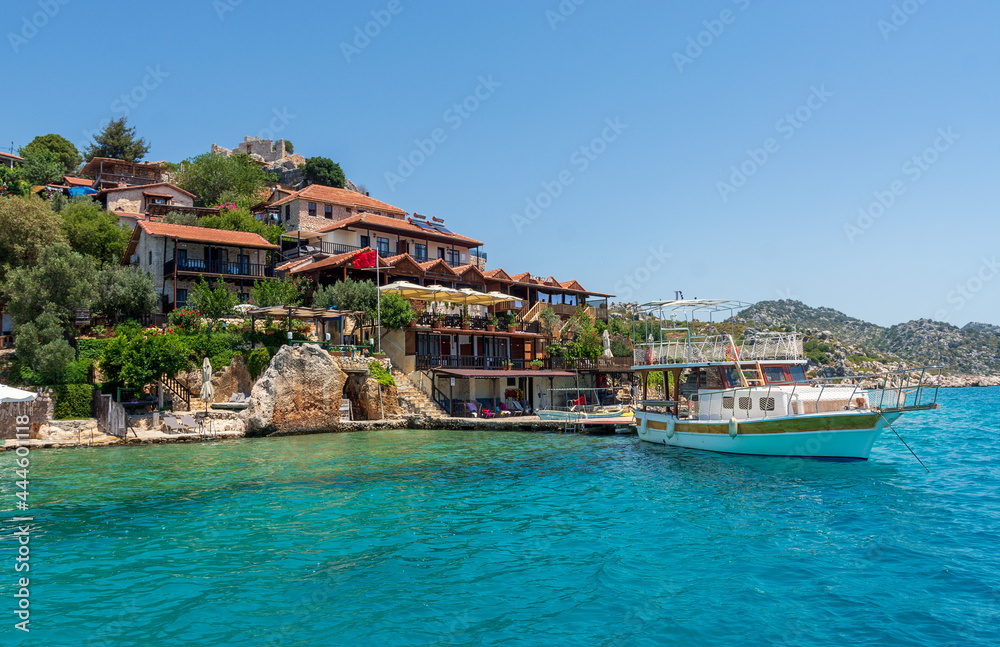 Village on the seaside. Moored ship, yacht. Azure, clear water.