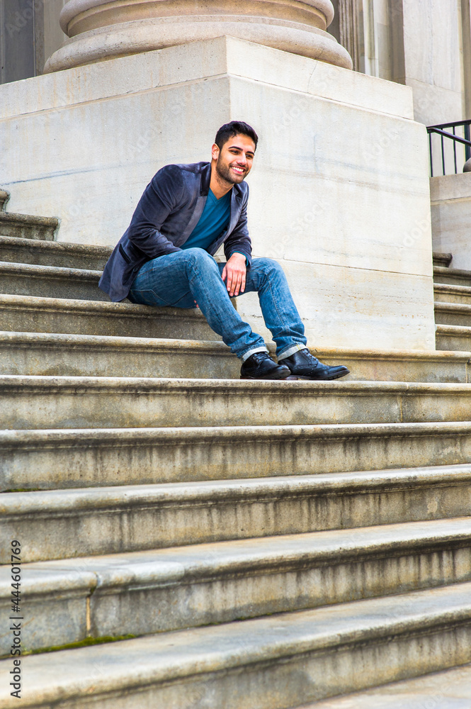 Dressing in a dark purple woolen blazer, blue jeans and black leather shoes, a young Middle Eastern guy with bread and mustache is sitting on steps, thinking and laughing. Dressing in a dark purple woolen blazer, blue jeans and black leather shoes, a young Middle Eastern guy with bread and mustache is sitting on steps, thinking and laughing.