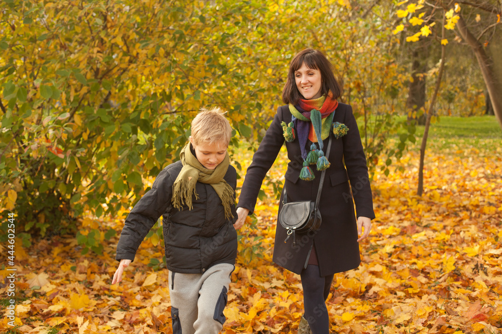 Mother and her son child boy walking in autumn park Mother and her son child boy walking in autumn park