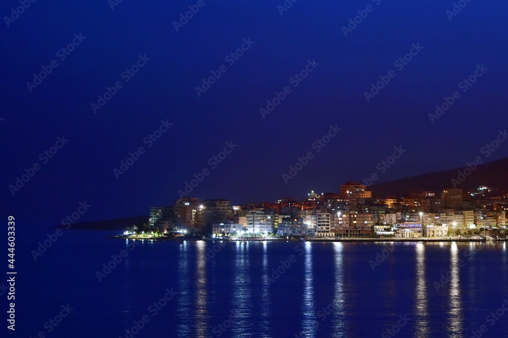 Night landscape of sea city with reflection of lights in water of the bay
