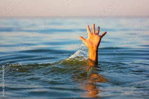 A man is drowning in water. A hand peeks out from under a water. A drowning person needs help, rescue. A risk, danger for living in the sea, river, ocean, pond. Death, SOS concept. Drowning victim