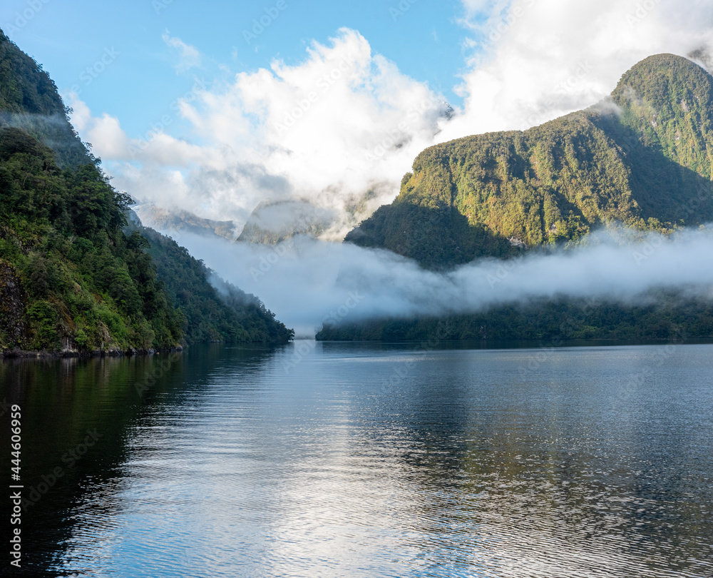 A new morning dawning at Doutful Sound, clouds hanging low in the mountains, Fiordland National Park, New Zealand