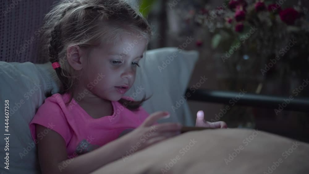Portrait Cute Little Girl Using Smartphone. Young Female Browses Internet, Checks Social Media Watching Video Little Child Spending Time Technology Light From Phone Screen Reflected On Her Face Portrait Cute Little Girl Using Smartphone. Young Female Browses Internet, Checks Social Media Watching Video Little Child Spending Time Technology Light From Phone Screen Reflected On Her Face