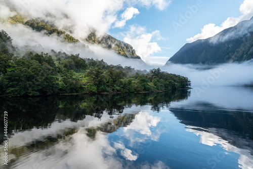 A new morning dawning at Doutful Sound, clouds hanging low in the mountains, Fiordland National Park, New Zealand