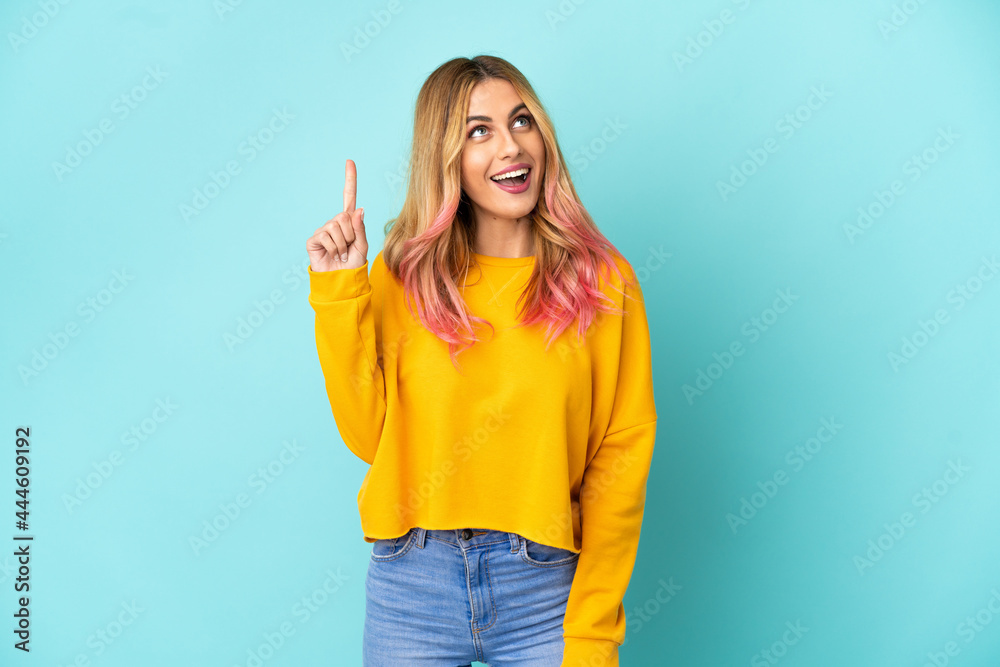 Young woman over isolated blue background pointing up and surprised Young woman over isolated blue background pointing up and surprised