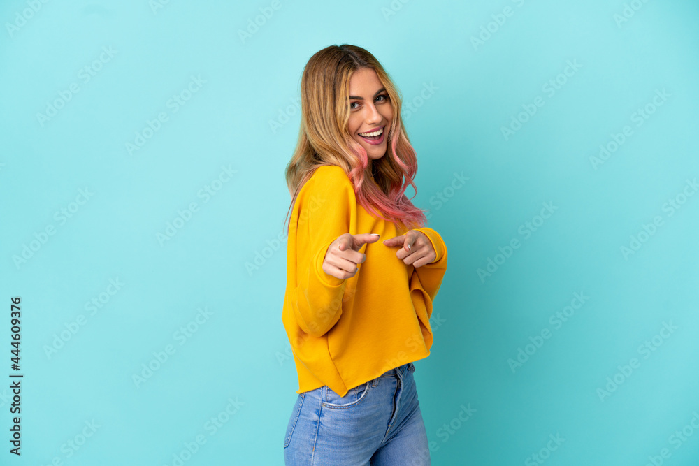 Young woman over isolated blue background surprised and pointing front Young woman over isolated blue background surprised and pointing front