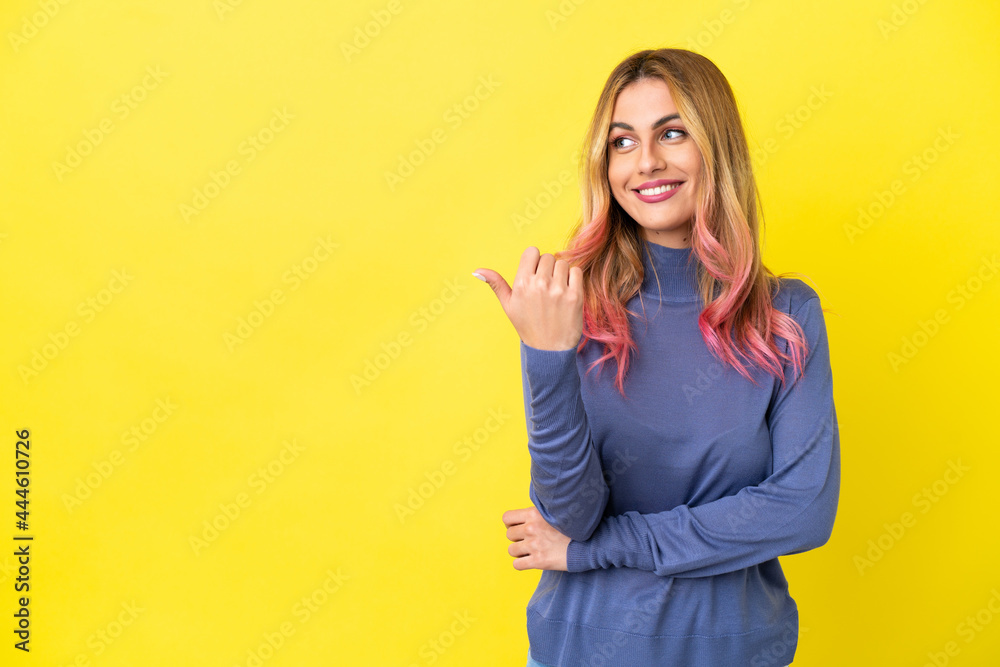 Young woman over isolated yellow background pointing to the side to present a product Young woman over isolated yellow background pointing to the side to present a product