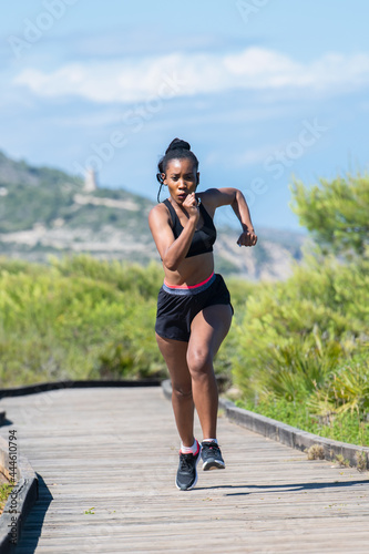 Afro american woman running fast along a wooden runway: Exercise concept.