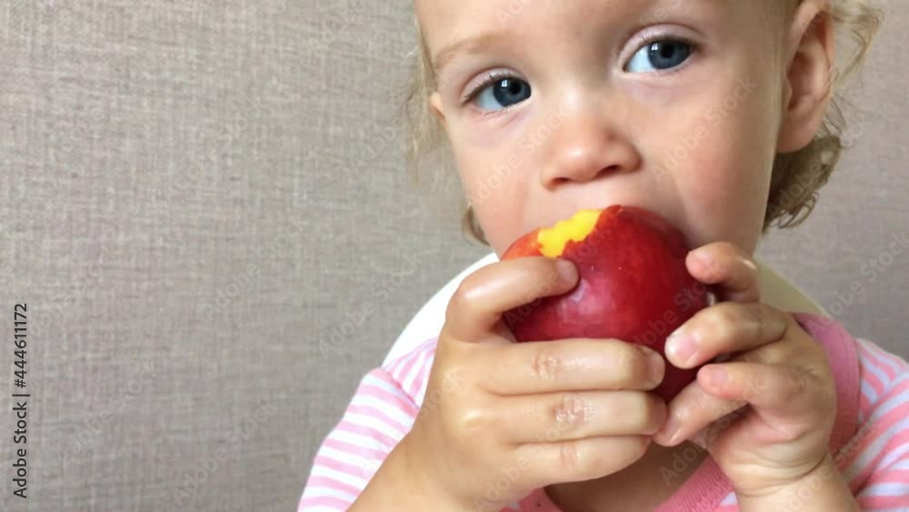 little girl tastes and eats juicy nectarine with pleasure and interest. High quality 4k footage little girl tastes and eats juicy nectarine with pleasure and interest. High quality 4k footage