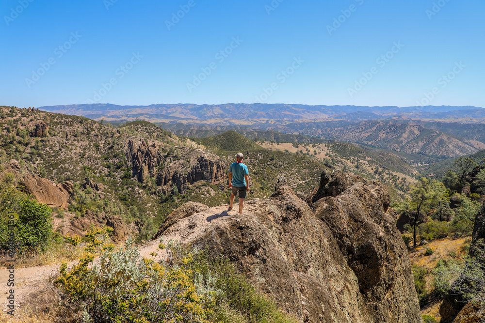 Man standing on rock ledge  overlooking  the landscape of Pinnacles National Park in California
