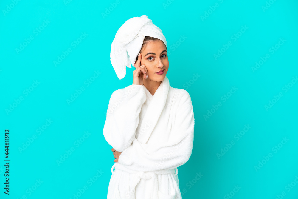 Young woman in a bathrobe over isolated blue background thinking an idea Young woman in a bathrobe over isolated blue background thinking an idea