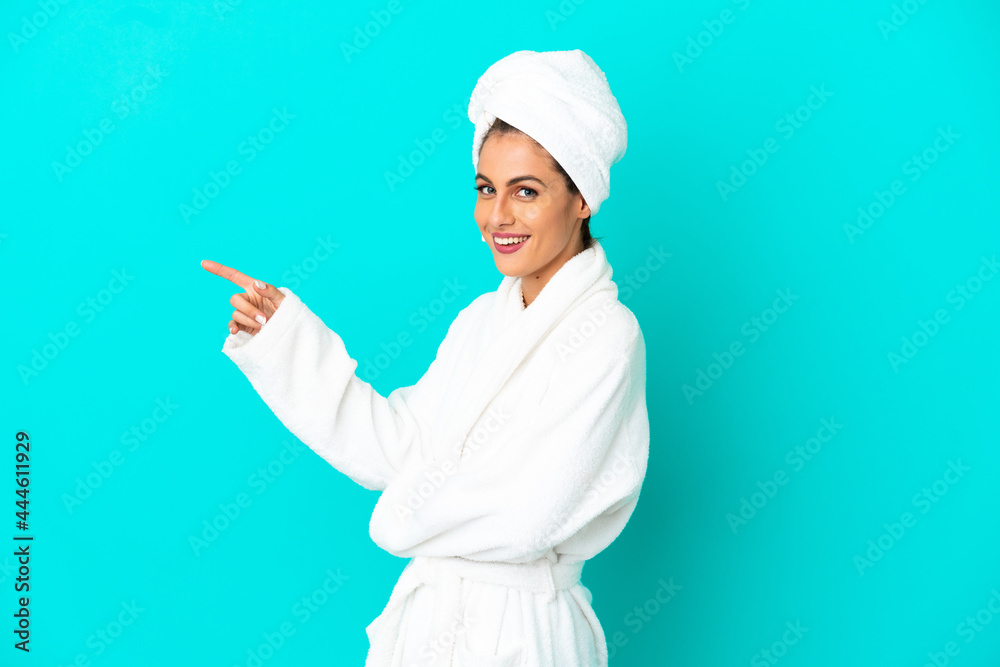 Young woman in a bathrobe over isolated blue background pointing finger to the side Young woman in a bathrobe over isolated blue background pointing finger to the side