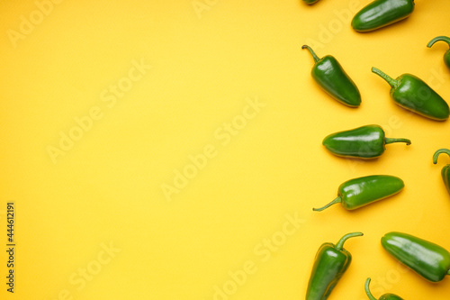 Green chili pepper. Group of jalapeno peppers on a yellow background, place for text, top view.