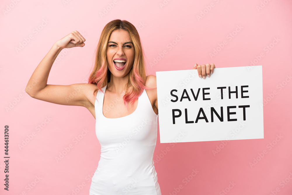 Young woman over isolated pink background holding a placard with text Save the Planet and doing strong gesture Young woman over isolated pink background holding a placard with text Save the Planet and doing strong gesture