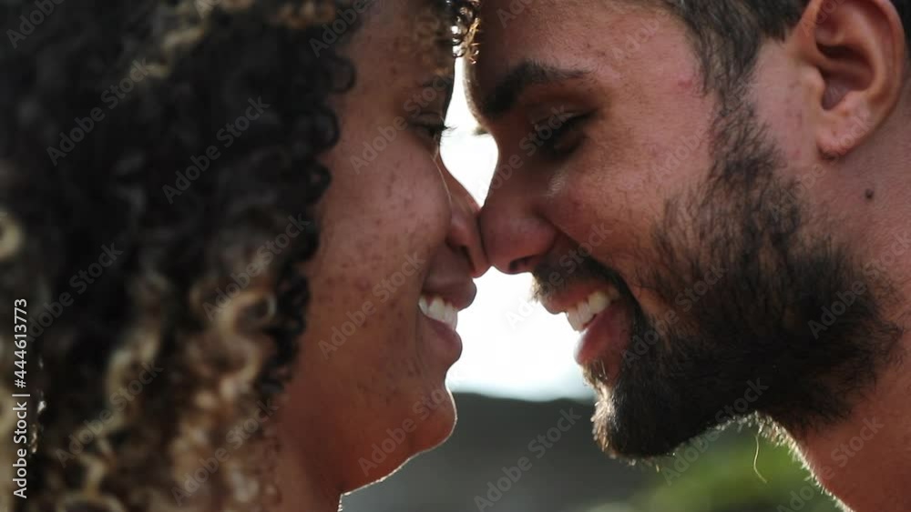 Hispanic couple kissing outside with lens-flare. South American lovers eskimo kiss