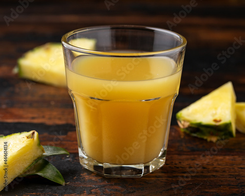 Freshly squeezed Pineapple juice in glass jug and two glasses on rustic wooden table