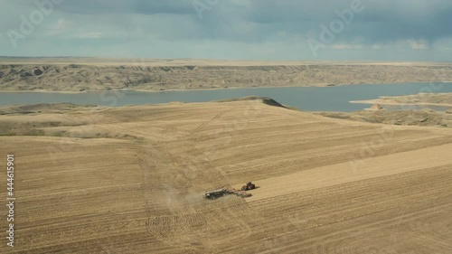 Golden rural landscape of Saskatchewan with tractor seeding field, aerial photo