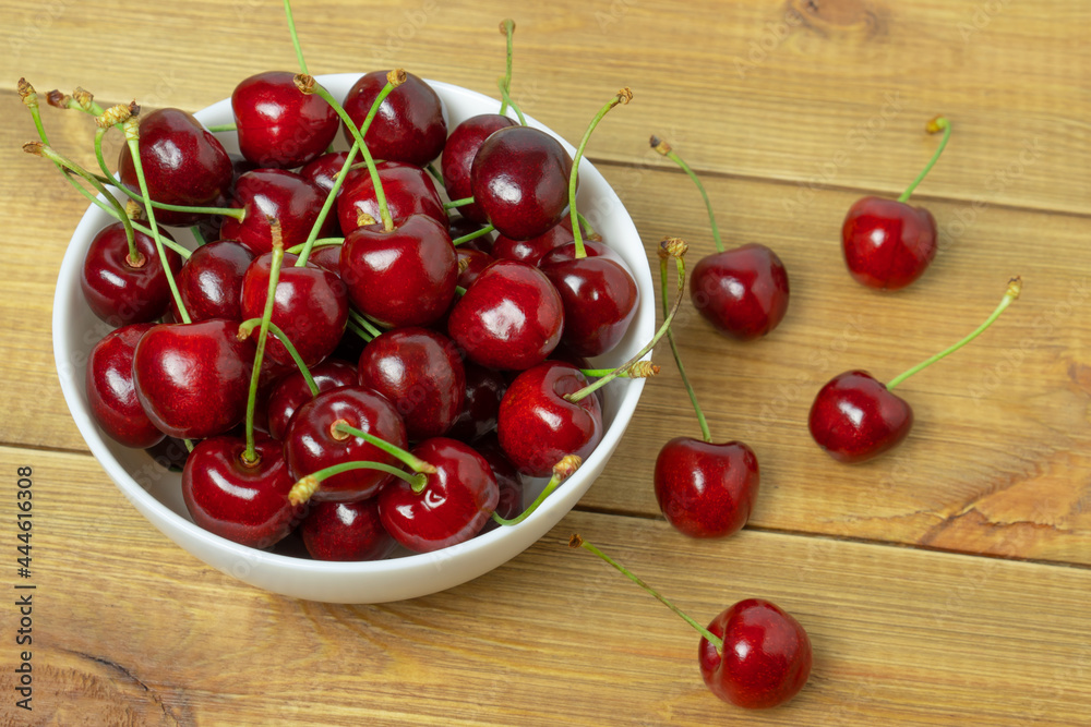 Ripe delicious sweet cherry berries in a bowl on wooden table. Ripe delicious sweet cherry berries in a bowl on wooden table.