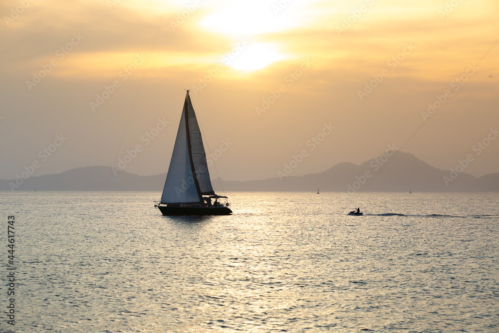 A sailboat and a jet ski sailing during a sunset in Santos