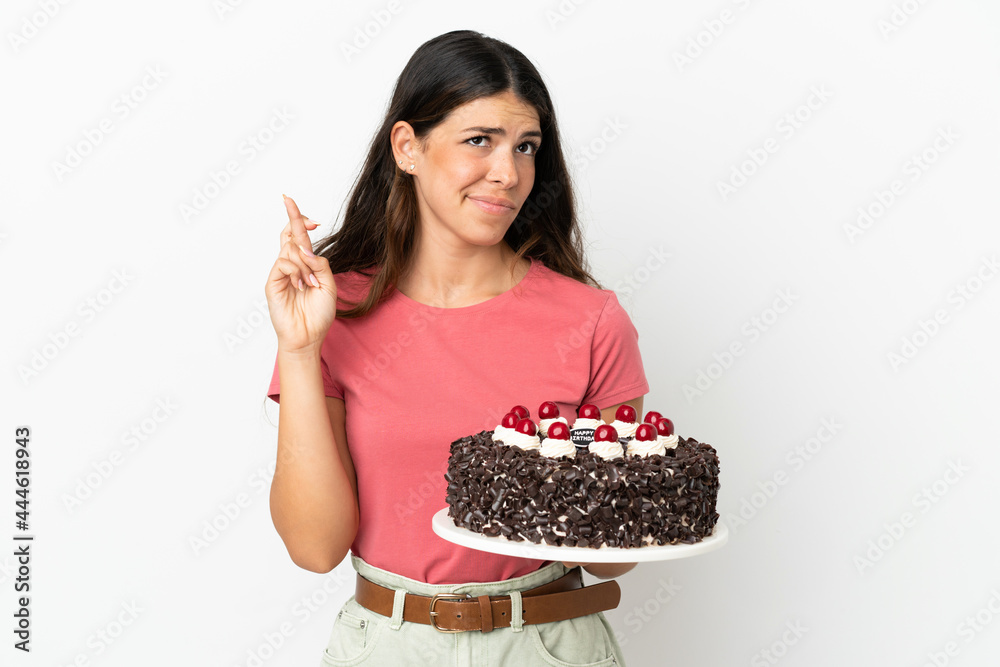 Young caucasian woman holding birthday cake isolated on white background with fingers crossing and wishing the best Young caucasian woman holding birthday cake isolated on white background with fingers crossing and wishing the best