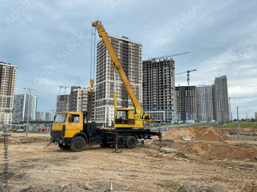 Large yellow mobility modern industrial construction crane mounted on a truck is used in the construction of new housing, houses, buildings in a big city