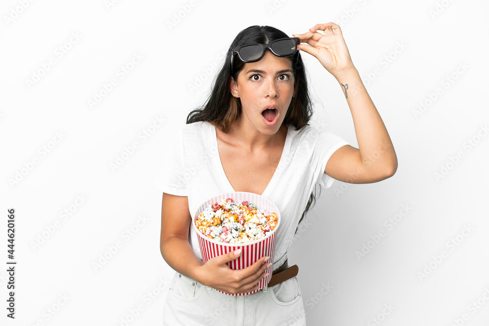 Young caucasian woman isolated on white background surprised with 3d glasses and holding a big bucket of popcorns Young caucasian woman isolated on white background surprised with 3d glasses and holding a big bucket of popcorns