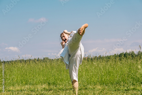 teenage girl training karate kata outdoors, performs the yoko geri kick with kiai photo