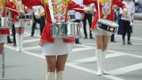 Street performance of festive march of drummers girls in red costumes on city street. Young girls drummer in red vintage uniform at the parade