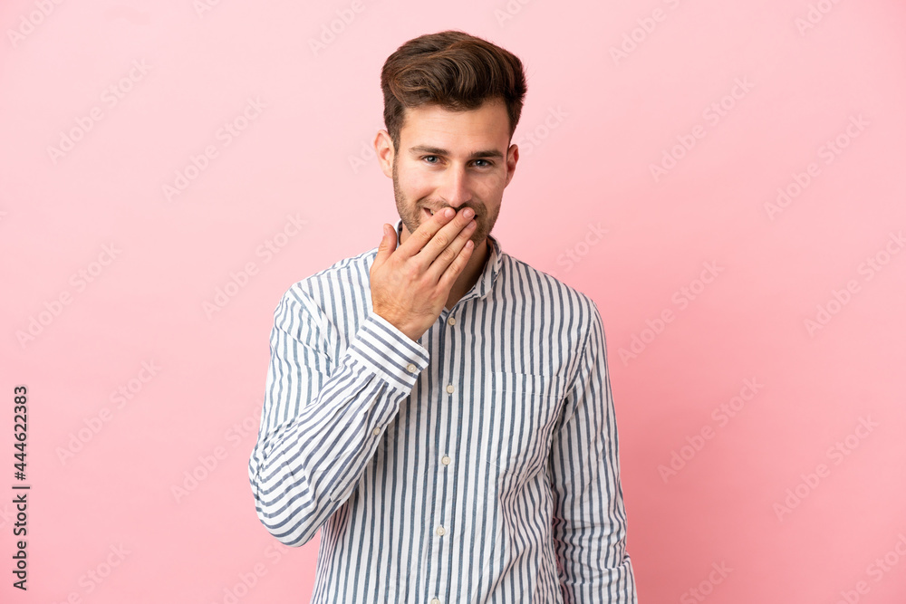 Young caucasian handsome man isolated on pink background happy and smiling covering mouth with hand