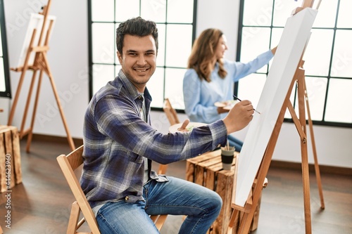 Two hispanic students smiling happy painting at art school.