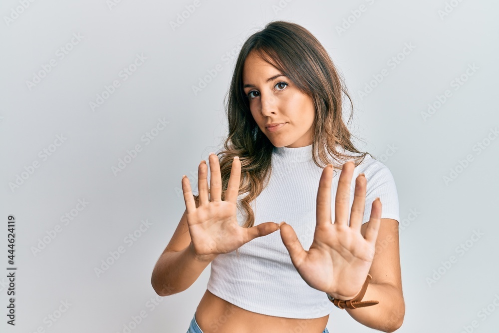 Young brunette woman wearing casual white t shirt moving away hands palms showing refusal and denial with afraid and disgusting expression. stop and forbidden. Young brunette woman wearing casual white t shirt moving away hands palms showing refusal and denial with afraid and disgusting expression. stop and forbidden.