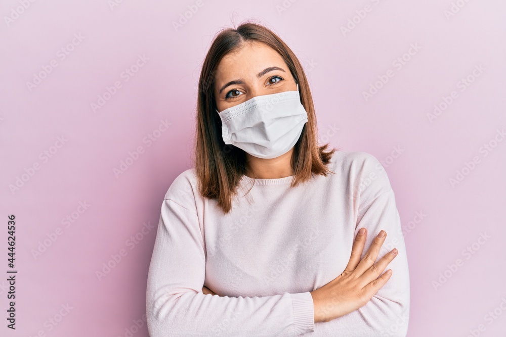Young beautiful woman wearing medical mask happy face smiling with crossed arms looking at the camera. positive person. Young beautiful woman wearing medical mask happy face smiling with crossed arms looking at the camera. positive person.