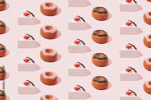Plastic sweets. Donuts with chocolate and pink glaze and strawberry cake on a pink background.