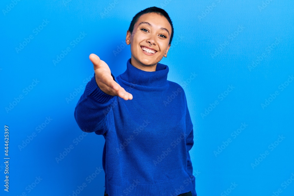 Beautiful hispanic woman with short hair wearing turtleneck sweater smiling friendly offering handshake as greeting and welcoming. successful business. Beautiful hispanic woman with short hair wearing turtleneck sweater smiling friendly offering handshake as greeting and welcoming. successful business.