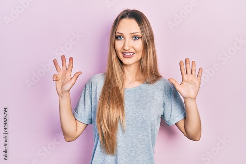 Young blonde girl wearing casual t shirt showing and pointing up with fingers number nine while smiling confident and happy.