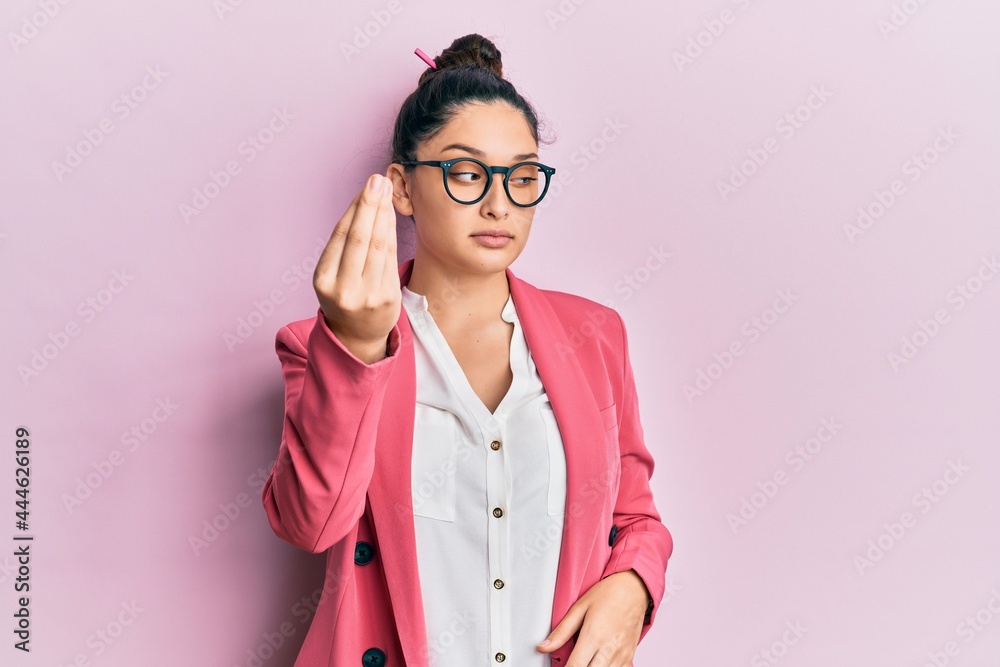 Beautiful middle eastern woman wearing business jacket and glasses doing italian gesture with hand and fingers confident expression