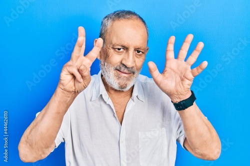 Handsome senior man with beard wearing casual white shirt showing and pointing up with fingers number eight while smiling confident and happy.