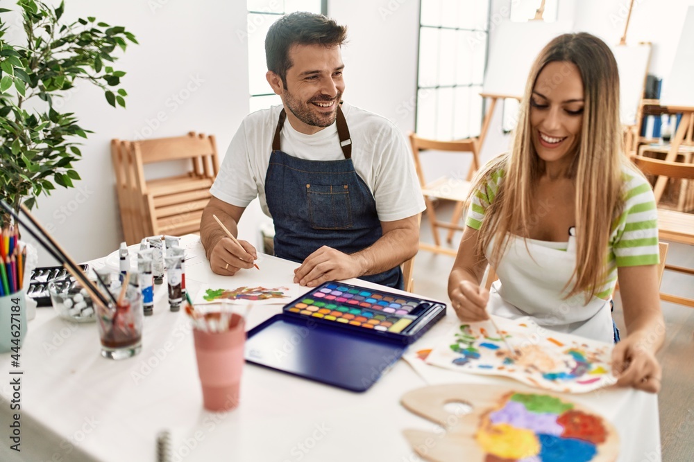 Fototapeta premium Two students smiling happy painting sitting on the table at art school.