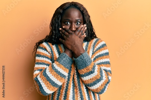 African young woman wearing wool winter sweater shocked covering mouth with hands for mistake. secret concept. © Krakenimages.com
