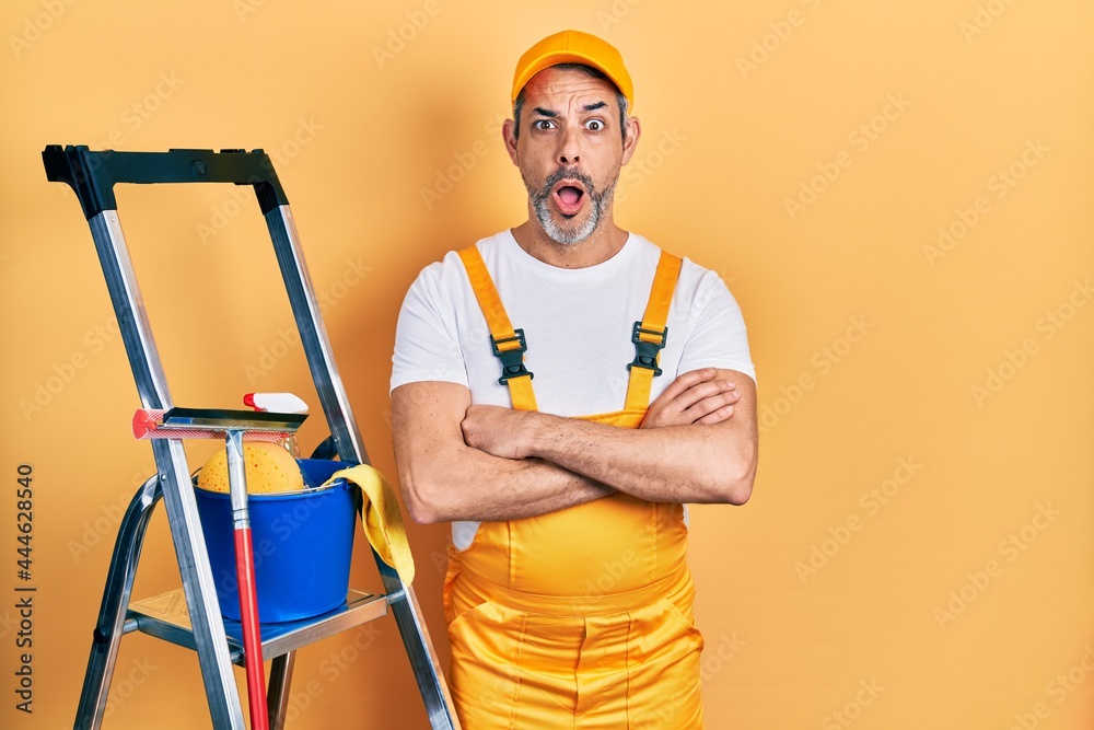 Handsome middle age man with grey hair window cleaner crossing arms afraid and shocked with surprise and amazed expression, fear and excited face.