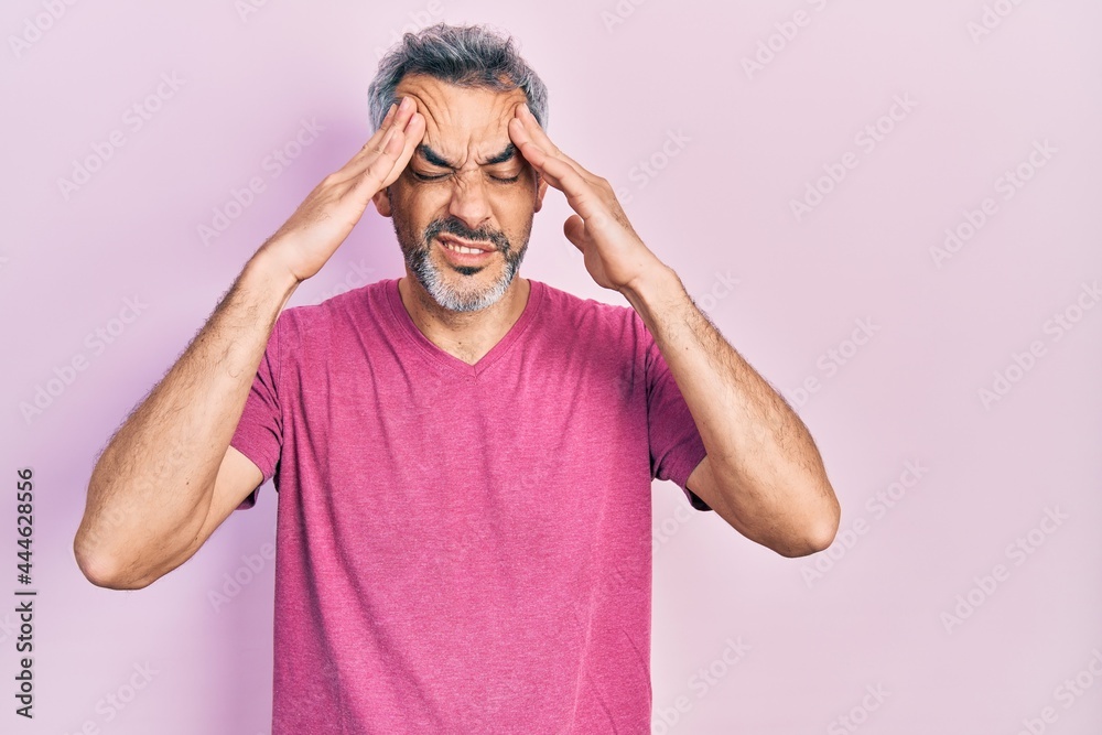 Handsome middle age man with grey hair wearing casual pink t shirt with hand on head, headache because stress. suffering migraine. Handsome middle age man with grey hair wearing casual pink t shirt with hand on head, headache because stress. suffering migraine.