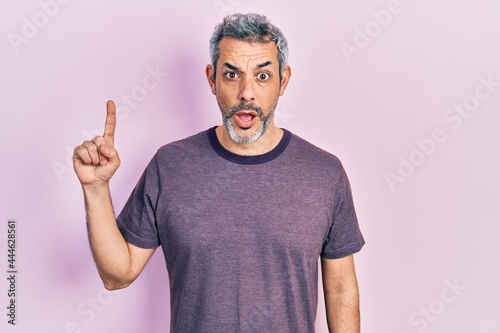 Handsome middle age man with grey hair pointing with index finger afraid and shocked with surprise and amazed expression  fear and excited face.