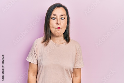 Middle age hispanic woman wearing casual clothes making fish face with lips, crazy and comical gesture. funny expression.