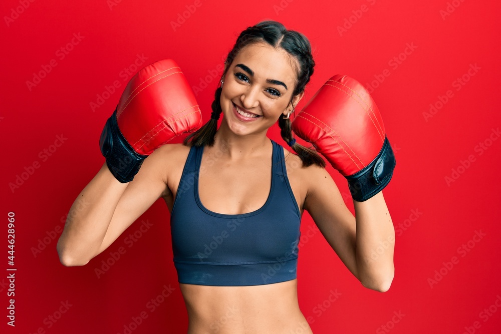 Young brunette girl using boxing gloves wearing braids smiling with a happy and cool smile on face. showing teeth.
